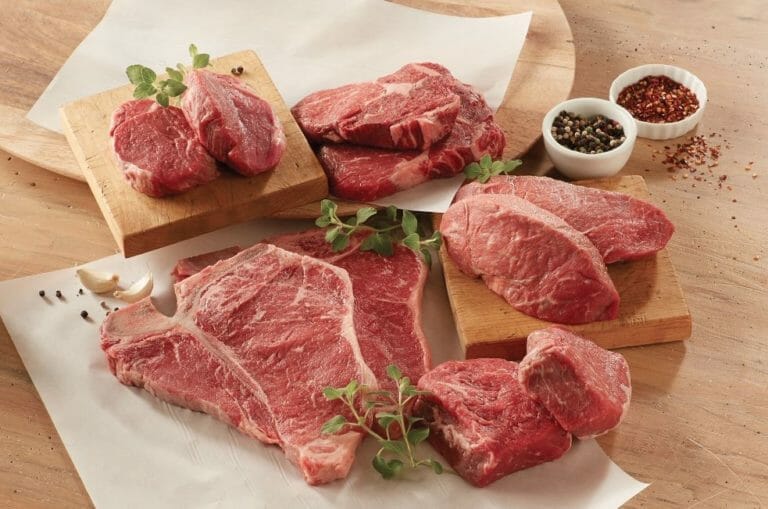 A steak sampler including two each of five different cuts displayed on wooden boards, with peppercorns and garnish.