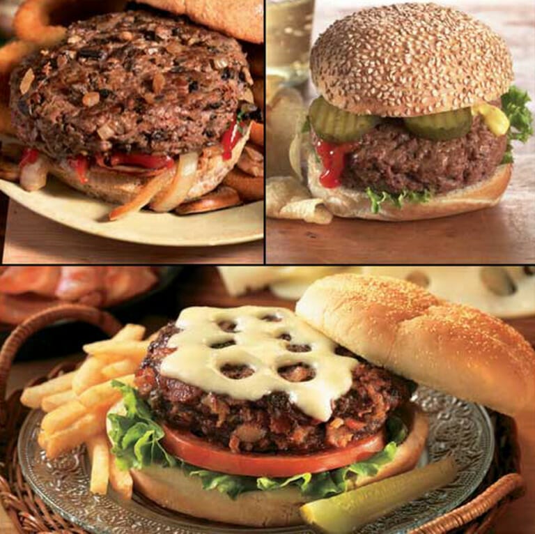Three grilled burger sandwiches on buns with various garnishes such as Swiss cheese, sauteed onions, and pickles.