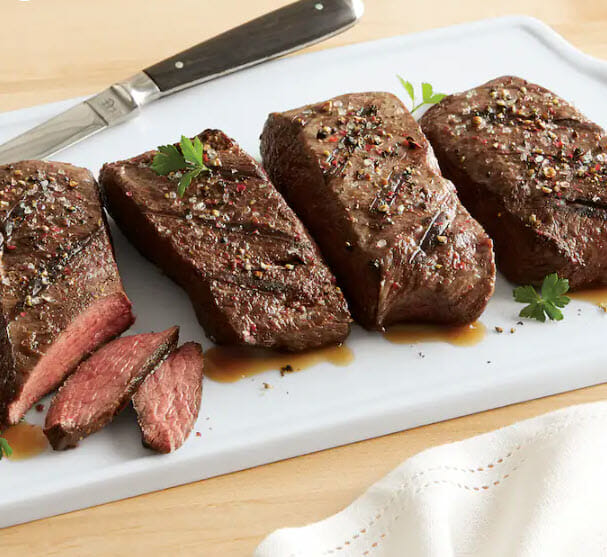 Four seasoned flat iron steaks on white cutting board
