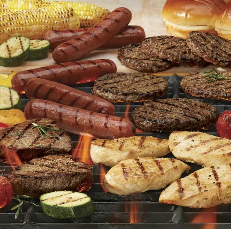 variety of meats on a grill, including steak, chicken, hamburgers and hot dogs.