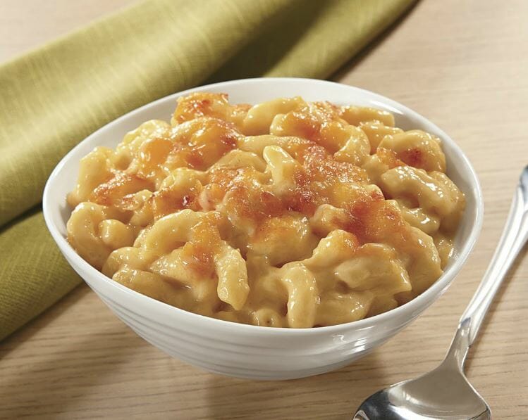 Mac and Cheese in a white bowl with a spoon and a light green napkin to the side.
