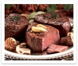 A white platter of three grilled Filet-Mignon steaks, with mushrooms and a garnish.