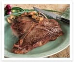 Broiled T-bone steak on a light green plate with button mushrooms and a steak knife.